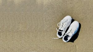 Baskets posées sur le sable en été, symbole de pieds échauffés par la chaleur et du besoin de les rafraîchir.