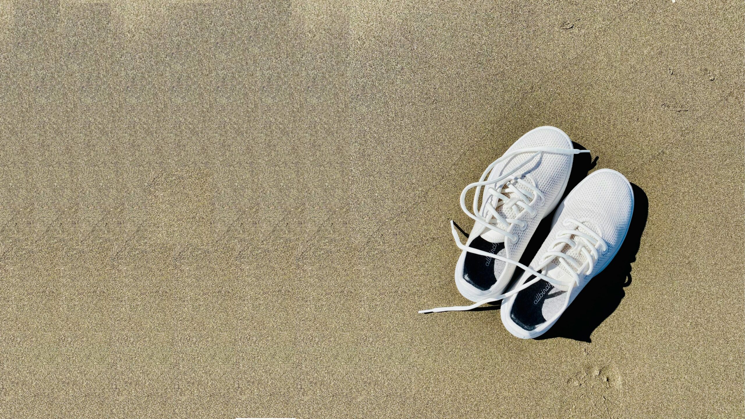Baskets posées sur le sable en été, symbole de pieds échauffés par la chaleur et du besoin de les rafraîchir.